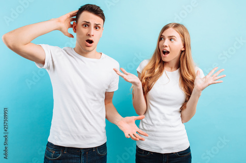 of an uncertain and perplexed couple, a man and a woman, in white t-shirts, against a blue background
