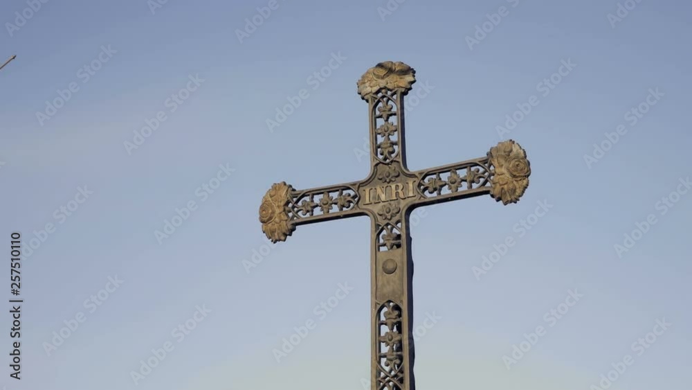 Metal cross with inscription INRI. Christian catholic symbol of faith. Bright blue sky in background, day shot Metal cross with inscription INRI. Christian catholic symbol of faith. Bright blue sky in background, day shot
