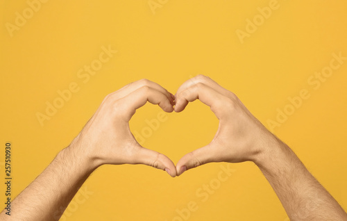 Man making heart with his hands on color background  closeup