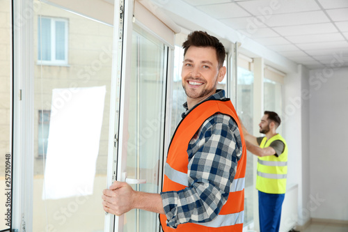 Tableau sur toile Construction workers installing plastic windows in house