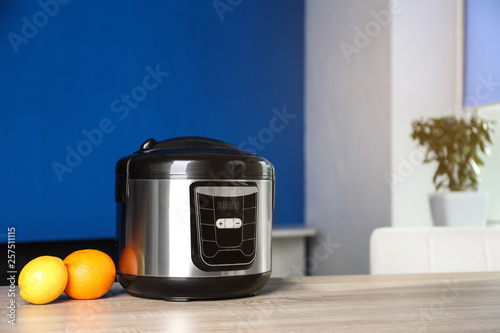 Modern multi cooker and ingredients on table indoors, space for text
