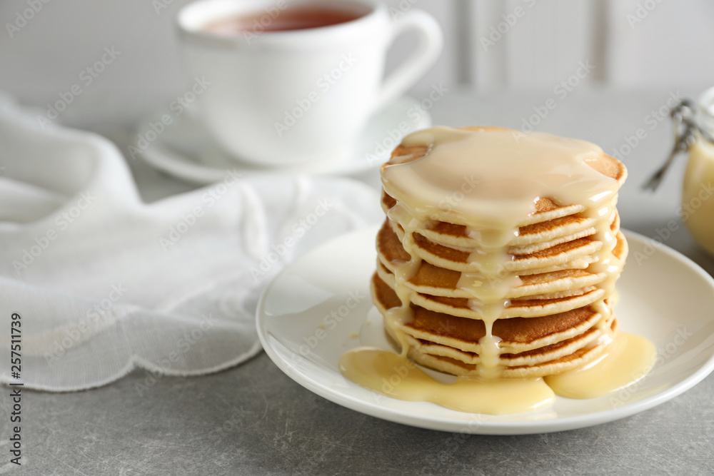 Plate with pancakes and condensed milk served on table, space for text. Dairy product Plate with pancakes and condensed milk served on table, space for text. Dairy product
