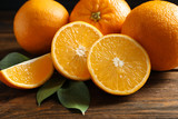 Fresh oranges with leaves on wooden table, closeup