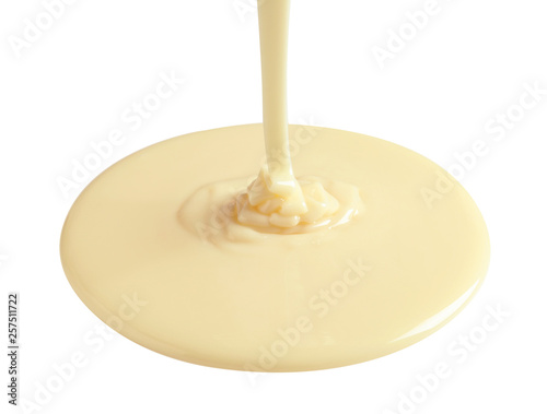 Tasty pouring condensed milk on white background. Dairy product