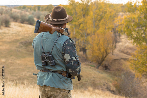 Hunter with a hat and a gun in search of prey in the steppe 