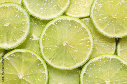 Juicy lime slices as background, top view. Citrus fruit