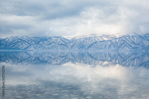 Lines from distant mountain ridges reflected in calm lake water