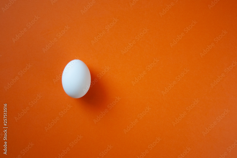 One single white egg on the bright red background with space for text. White easter egg minimal composition. Easter clean blank. One single white egg on the bright red background with space for text. White easter egg minimal composition. Easter clean blank.