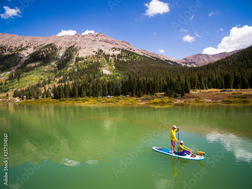 Couple paddling with their dog on paddle board at reservoir in mountains near Aspen, Colorado, USA photo