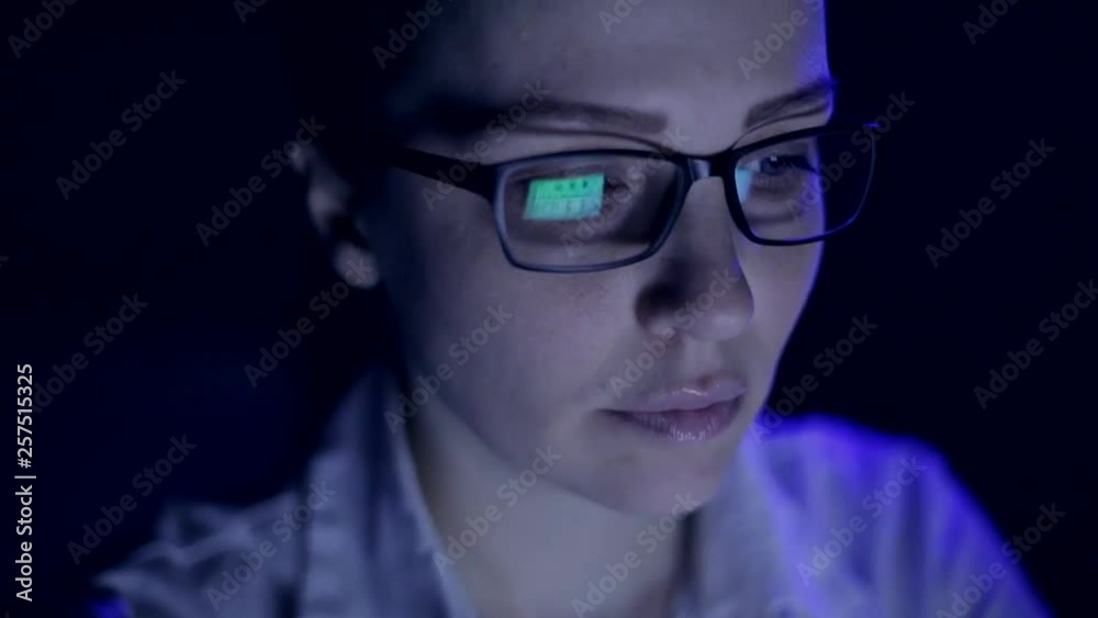 later a woman working at a laptop, monitor reflection in the glasses later a woman working at a laptop, monitor reflection in the glasses