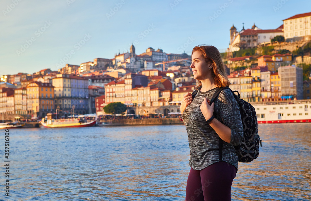 Obraz Young woman tourist enjoying beautiful landscape view on the old town (Ribeira historical quarter) and river Duoro during the sunset in Porto city, Portugal