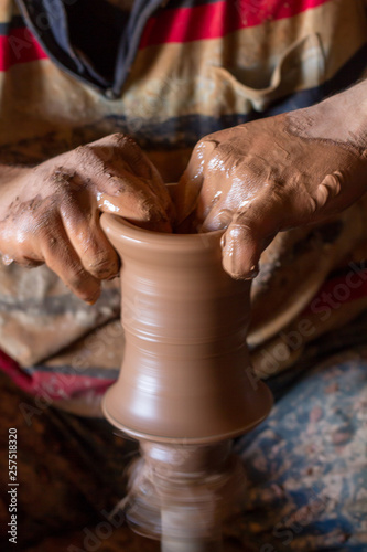 ceramic workshop - the man makes a pot of clay on a potter's wheel