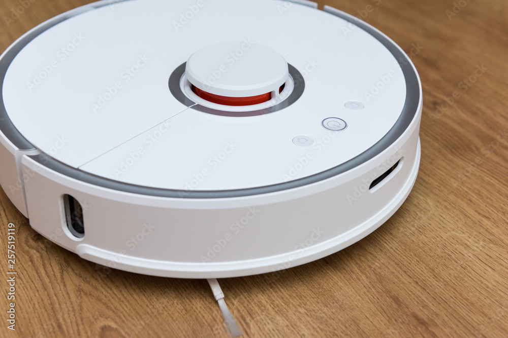Robotic vacuum cleaner on laminate wood floor. Smart cleaning technology Robotic vacuum cleaner on laminate wood floor. Smart cleaning technology