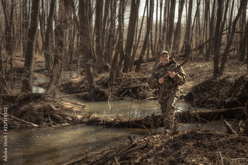 Hunter man forest river spring with shotgun during hunting season  