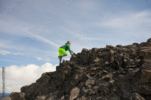 Side view of young boy scrambling up rocky mountain slope, Merritt, British Columbia, Canada