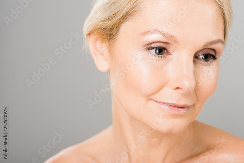 attractive and blonde mature woman looking away on isolated on grey