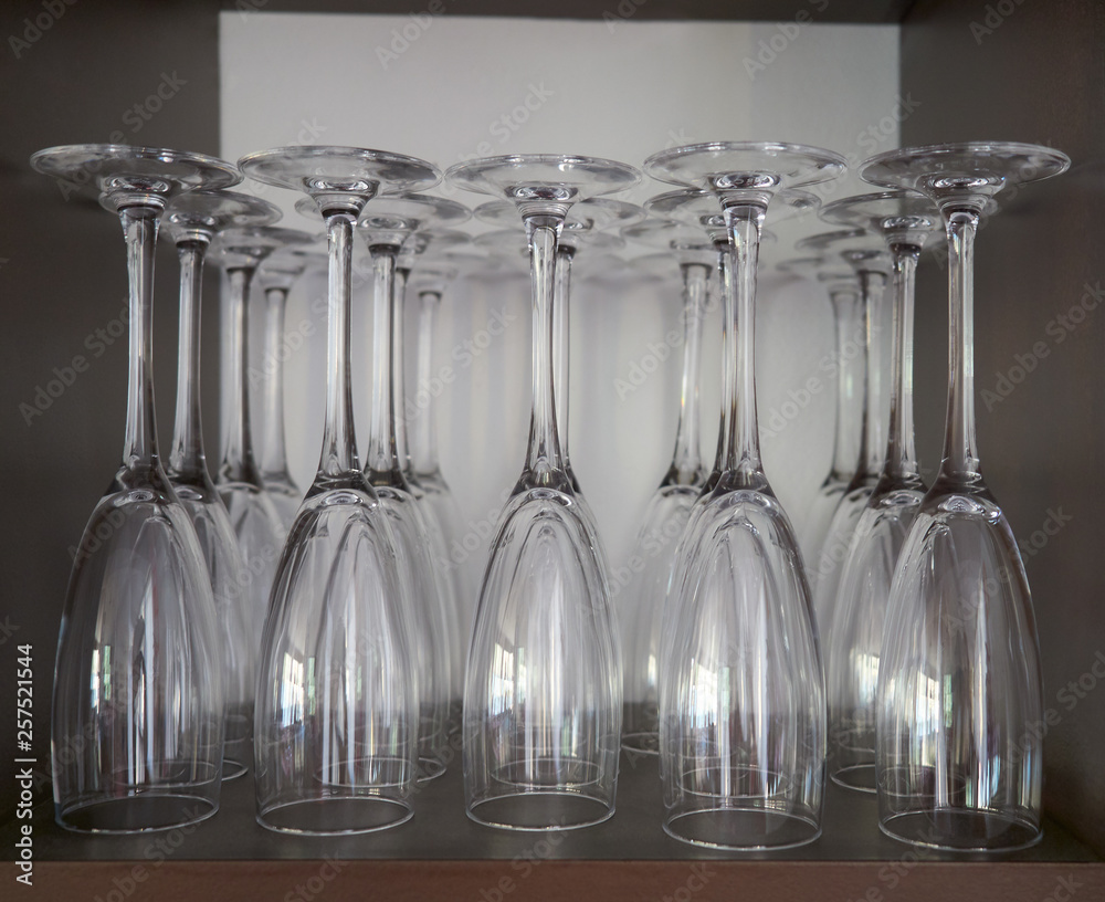 Selective focus view of an upside down row set of champagne and cocktail clean empty glasses waiting to be used in the cupboard of a restaurant of Spain Selective focus view of an upside down row set of champagne and cocktail clean empty glasses waiting to be used in the cupboard of a restaurant of Spain