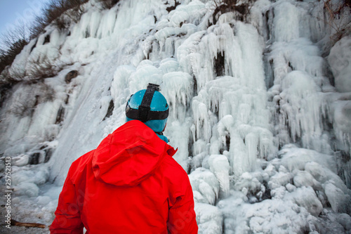 Rear view of climber in red jacket looking at hill in ice photo