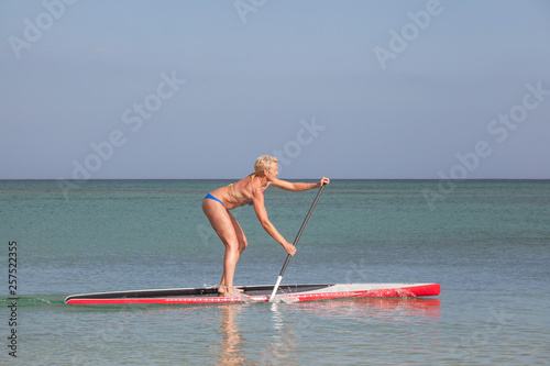 Sonni Honscheid, professional SUP surfer paddling on her race SUP (stand up paddle) board in bikini on flat clear water. Fuerteventura photo