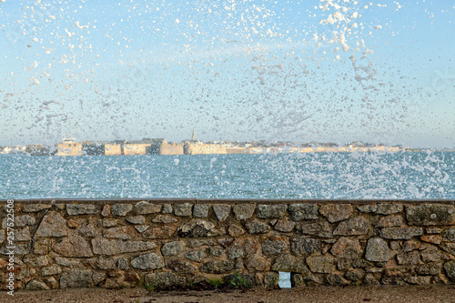 Water splashing after wave crashing on stone wall on coastline photo