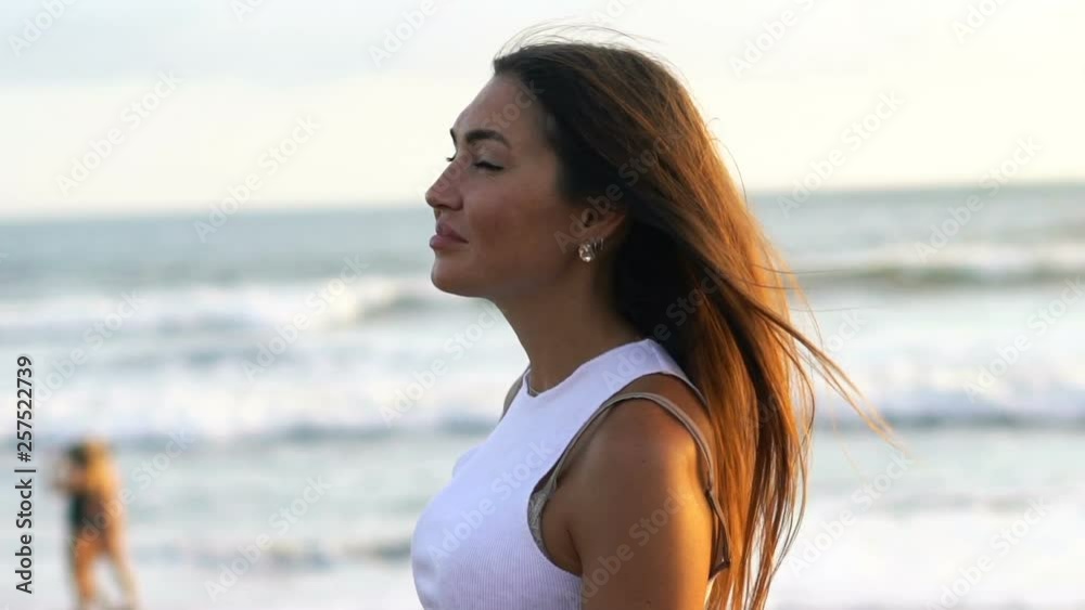 Portrait of young, happy woman standing on the beach, super slow motion Portrait of young, happy woman standing on the beach, super slow motion
