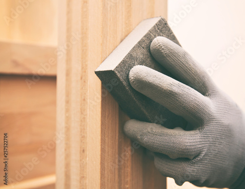 Wood grinding process by sandpaper. The young carpenter works with wood photo