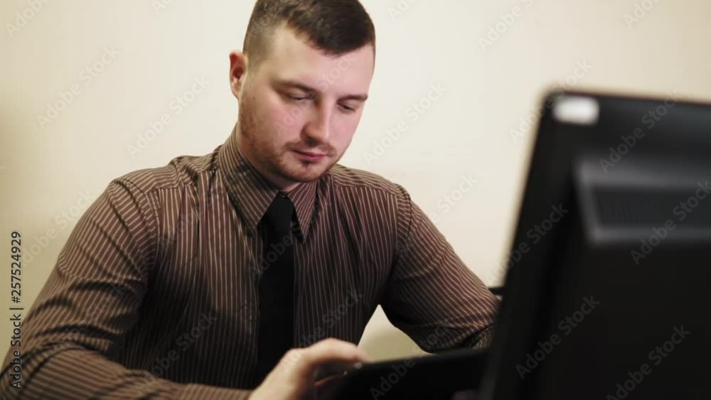 Office employee working on his tablet. Attractive male with beard Office employee working on his tablet. Attractive male with beard