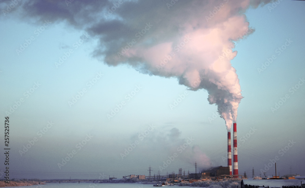 Factory brick chimney. The smoke from the pipe cogeneration plant. Steam escaping from a trumpet on the sky background. Ambient air pollution industrial emissions.