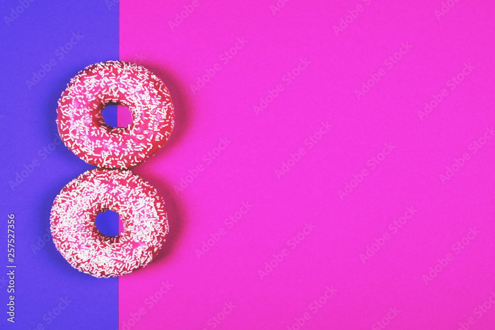 Tasty pink donut on a double-colored table.