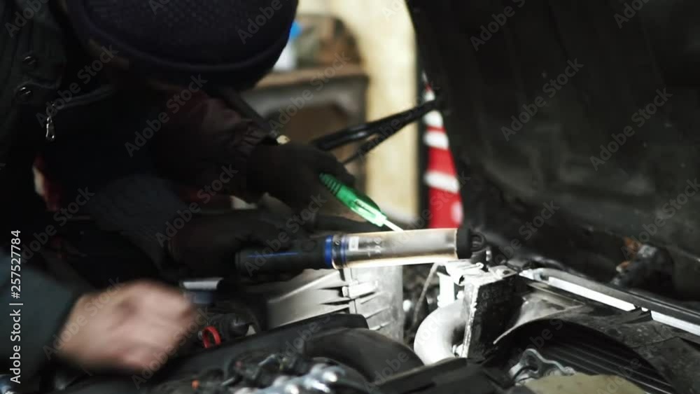 Mechanic searching a coolant leak under the car hood Mechanic searching a coolant leak under the car hood
