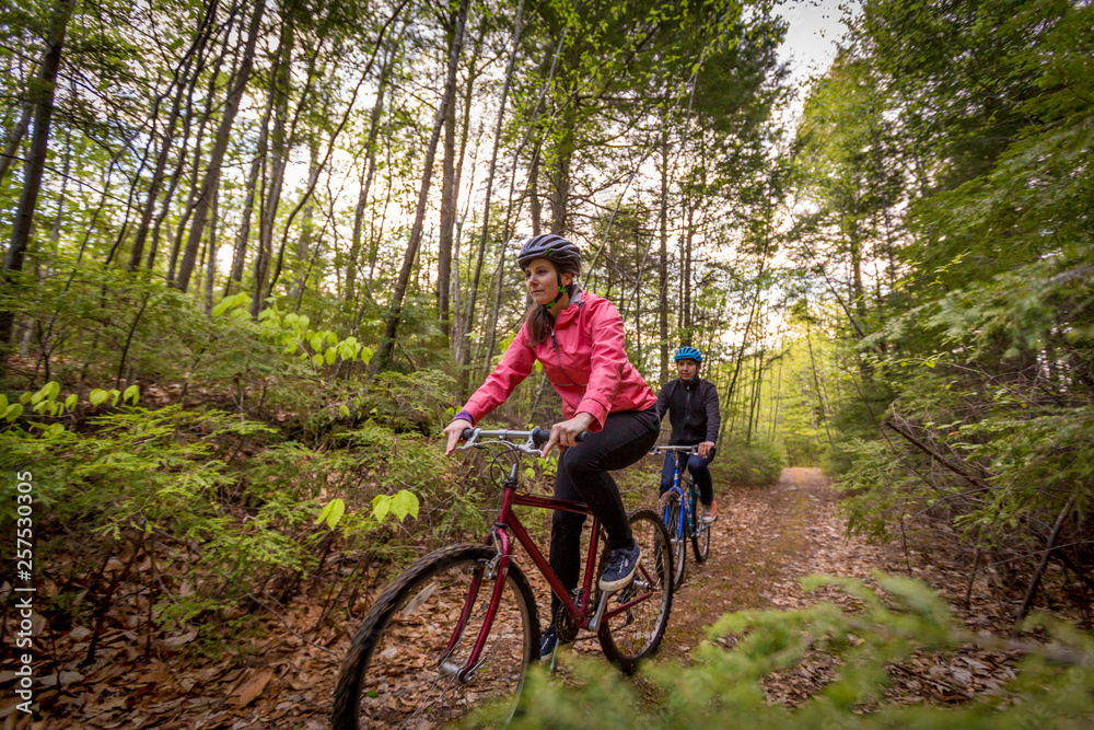 A couple mountain biking on a forest trail near Stonehouse Pond in Barrington, New Hampshire. A couple mountain biking on a forest trail near Stonehouse Pond in Barrington, New Hampshire.
