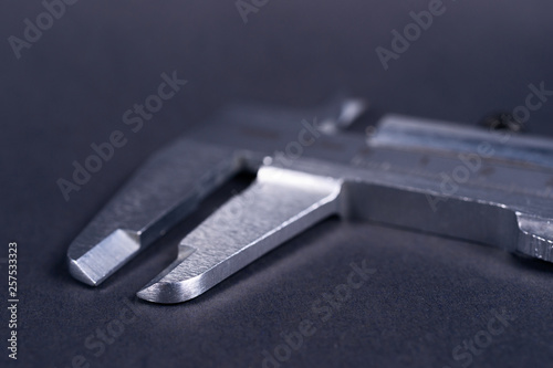 Vintage steel caliper tool closeup. Caliper tips in focus. Tool in very good condition. Scale in metric units, milimeter step. Stock photo on blurred gray background.