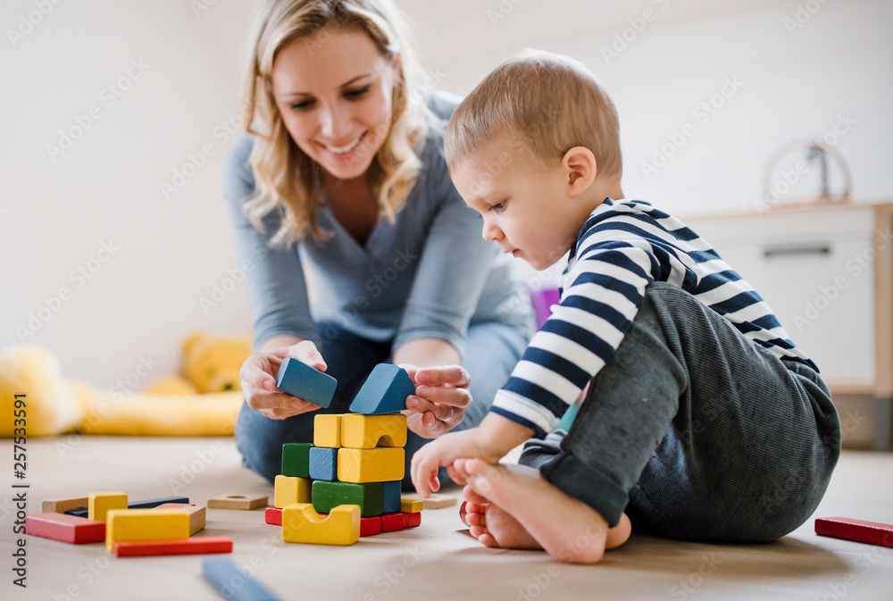Smiling mother and toddler son playing with building blocks at home Smiling mother and toddler son playing with building blocks at home