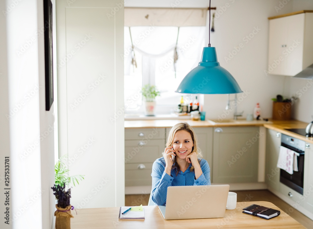 Smiling woman with laptop and cell phone working at home Smiling woman with laptop and cell phone working at home