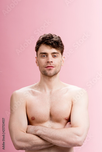 handsome, serious brunette man looking at camera on pink