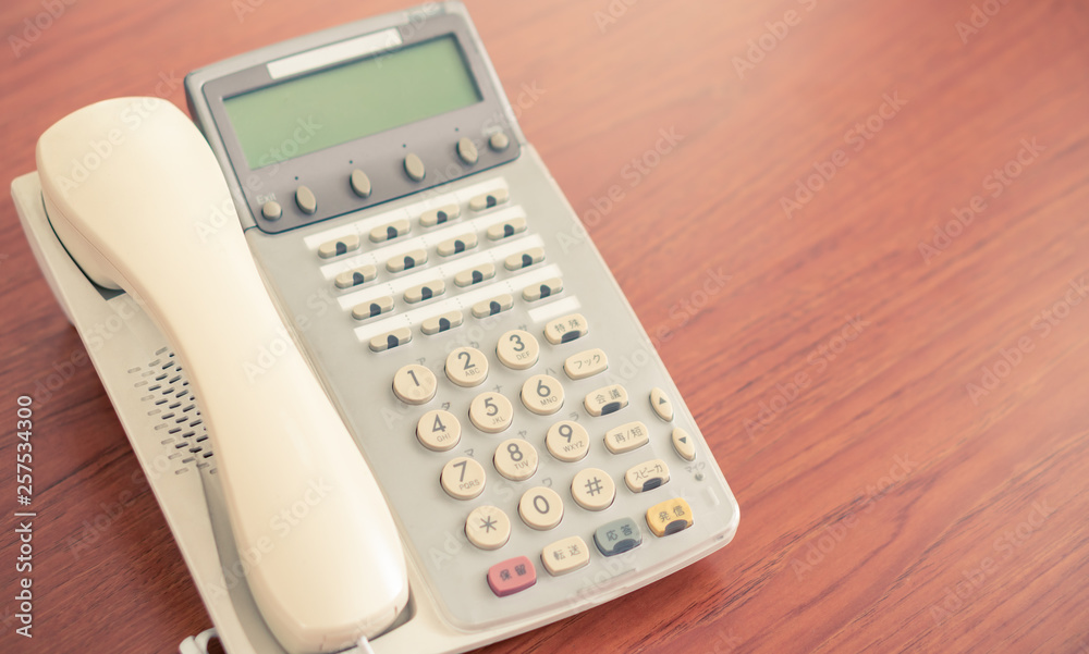 old office telephone on the desk for business communication, multi language retro interior 1990 style phone background with copy space old office telephone on the desk for business communication, multi language retro interior 1990 style phone background with copy space