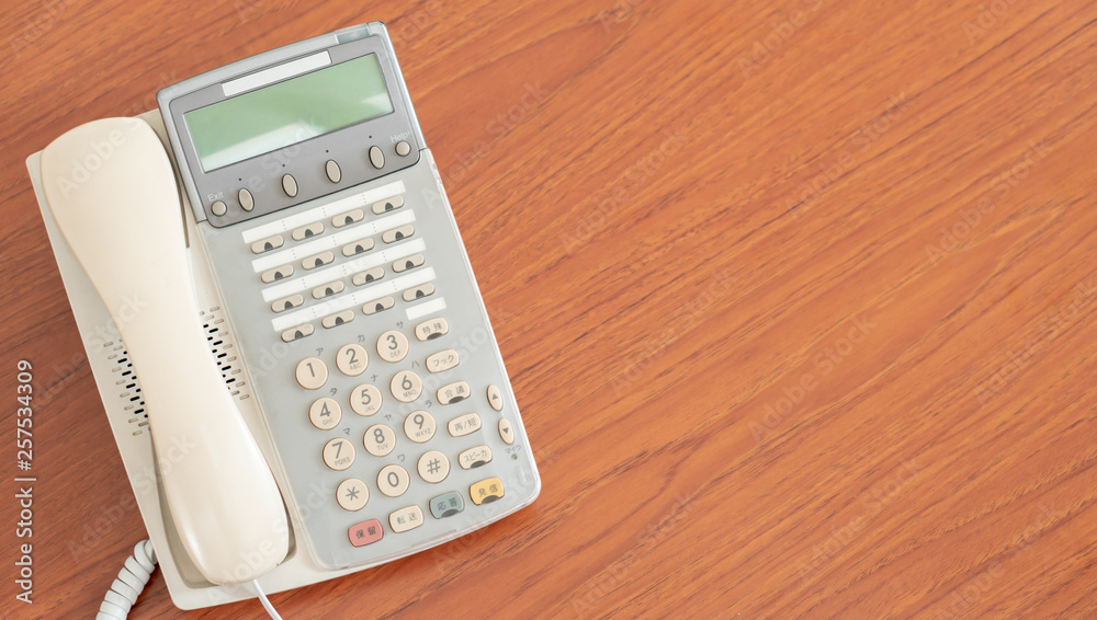 old office telephone on the desk for business communication, multi language retro interior 1990 style phone background with copy space old office telephone on the desk for business communication, multi language retro interior 1990 style phone background with copy space
