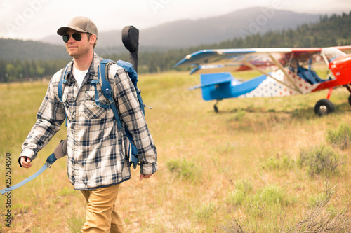 Man walking away form monoplane in wilderness