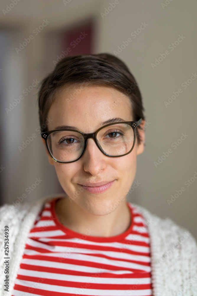 Portrait of a smiling young woman with short hair, wearing glasses Portrait of a smiling young woman with short hair, wearing glasses