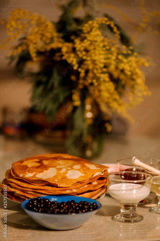 A stack of thin Russian hot pancakes blini  with currants, honey, sour cream and jam. Shrovetide Maslenitsa - traditional Russian holiday.