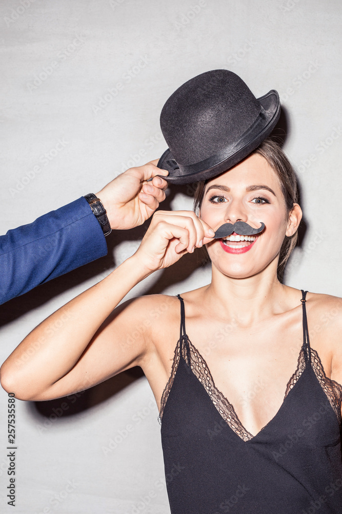 Portrait of young woman with bowler and fake moustache at a party Portrait of young woman with bowler and fake moustache at a party
