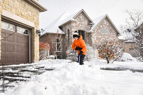 Boy shovelling snow off of a driveway after a winter storm