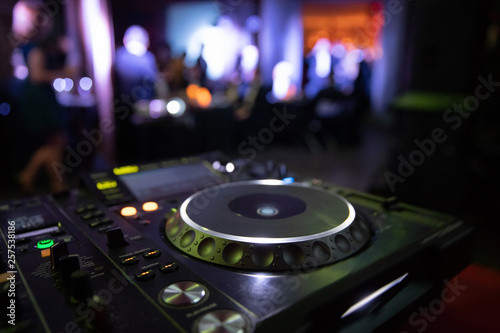 DJ console mixer at a nightclub. The disco, Banquet, people blurred background dancing. 