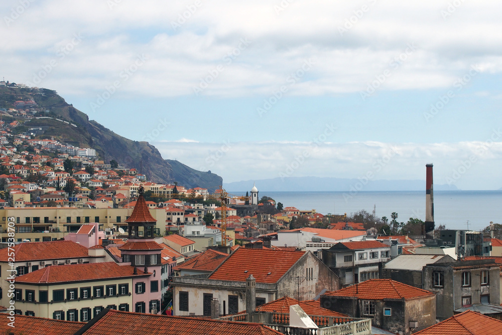 a panoramic rooftop view of the old town in funchal madeira with the sea and mountains in the distance