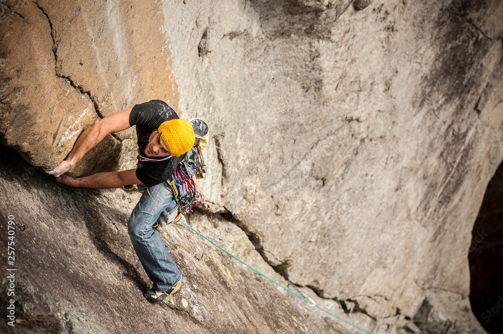 Man lead climbing a two pitches crack route in trad style  (that means that only self-placed gear like friends and nuts is allowed for protect the ascent) in Cadarese, Ossola Valley, Italy.