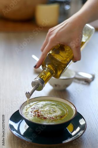Creamy vegetable soup with kale, cabbage, celery and millet, decorated with olive oil, yoghurt sauce and chilli flakes. Served with toasted bread and lemony yoghurt sauce. Selective focus.