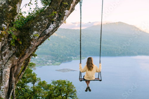 Woman sitting on swing against Lake Buyan, Bedugul, Bali, Indonesia