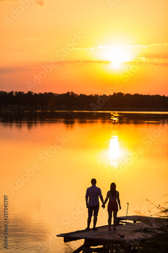 silhouette of woman and man, couple lover holding hand on the beach when the sun is rising