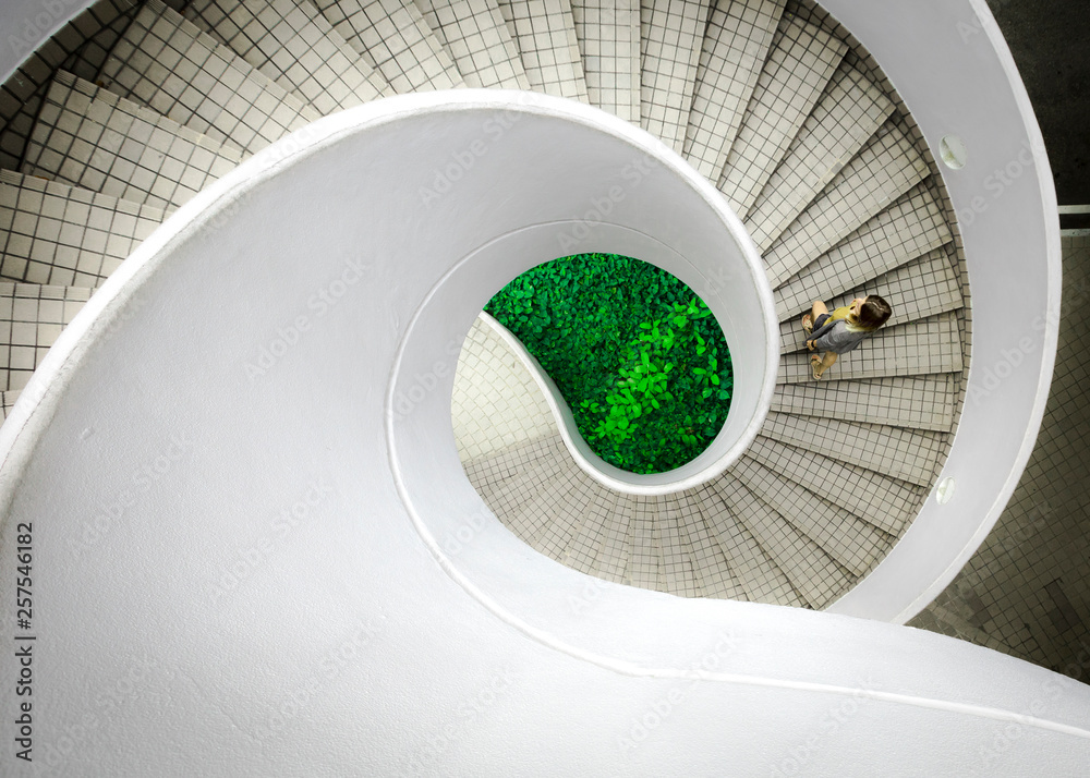 © Cavan Images - Woman walking up spiral staircase decorated with checked pattern © Cavan Images - Woman walking up spiral staircase decorated with checked pattern