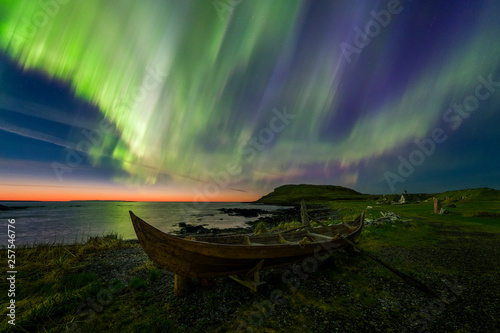 Northern Lights over rowboat on coastline in Viking village  photo